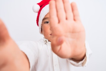 Poster - Beautiful kid boy wearing Christmas Santa hat make selfie over isolated white background with open hand doing stop sign with serious and confident expression, defense gesture