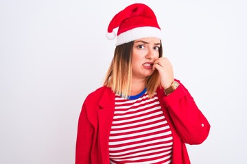 Sticker - Young beautiful woman wearing Christmas Santa hat over isolated white background looking stressed and nervous with hands on mouth biting nails. Anxiety problem.