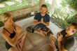 happy group of young hipster American friends enjoying Asian yoga retreat together sitting on lotus position meditating at outdoors hut in Bali in mind body harmony
