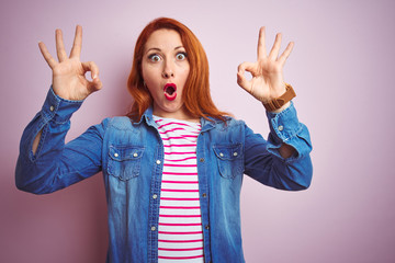 Canvas Print - Beautiful redhead woman wearing denim shirt and striped t-shirt over isolated pink background looking surprised and shocked doing ok approval symbol with fingers. Crazy expression