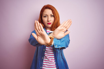 Sticker - Beautiful redhead woman wearing denim shirt and striped t-shirt over isolated pink background Rejection expression crossing arms and palms doing negative sign, angry face