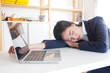 © TS.PHOTOS - Young Asian woman feeling tired in the office after working hard in front of her laptop. Resting and sleeping on her working table