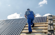Male Builder Performs Work On The Roof, Fastens Corrugated Sheets О