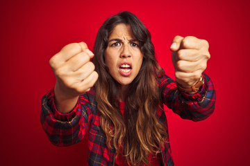 Wall Mural - Young beautiful woman wearing casual jacket standing over red isolated background Smiling cheerful playing peek a boo with hands showing face. Surprised and exited