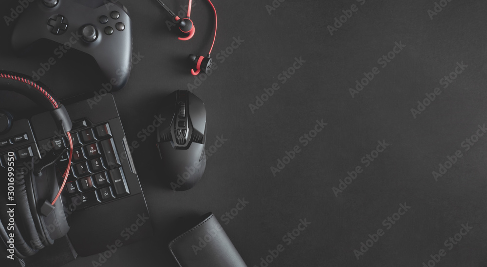 gamer work space concept, top view a gaming gear, mouse, keyboard, joystick, headset and in ear headphone on black table background. - obrazy, fototapety, plakaty 