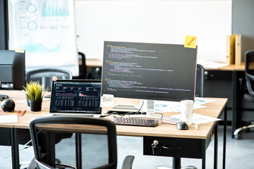 Programmer's working place with computers and programming code on the monitors in the office