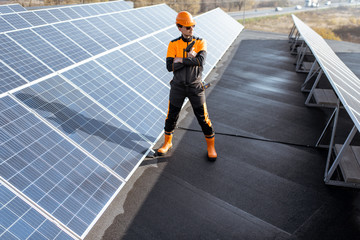 Wall Mural - portrait of a well-equipped worker in protective orange clothing examining solar panels on a photovo