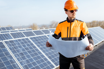Wall Mural - portrait of an engineer in protective workwear with blueprints of solar station project on a photovo