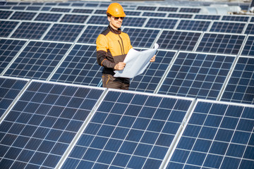 Wall Mural - engineer in protective workwear with blueprints of solar station project on a photovoltaic rooftop p