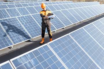 Wall Mural - view on the rooftop solar power plant with engineer in protective workwear walking and examining pho