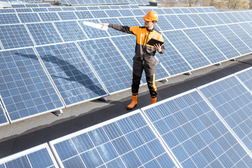 Wall Mural - view on the rooftop solar power plant with engineer in protective workwear walking and examining pho