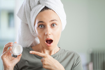 Poster - Young woman applying moisturizer to her skin.