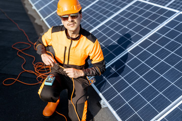 Wall Mural - well-equipped electrician connecting solar panels, checking the voltage and connecting wiring on a r