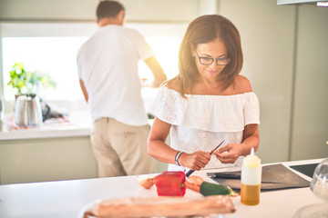 Sticker - Middle age beautiful couple cooking together on the kitchen