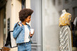 © mimagephotos - modern african american woman walking on street window shopping