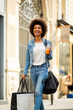 © mimagephotos - happy young woman walking in city with shopping bag and drink
