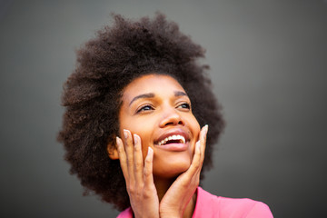 Wall Mural - Close up of beauty young african american woman smiling with hands on face against gray wall