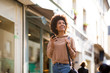 © mimagephotos - happy young black woman with mobile phone walking in city