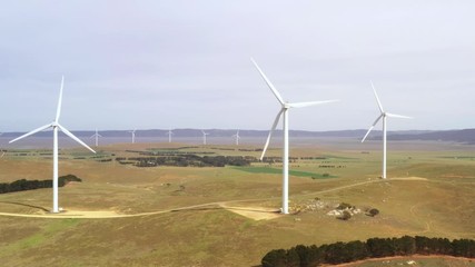 Wall Mural - aerial view of an array of large wind turbines rotating to create kinetic energy for renewable energ