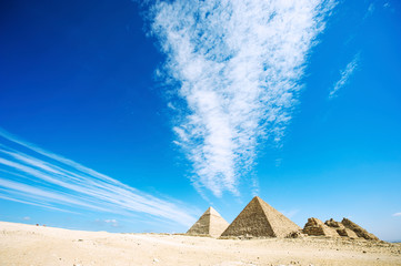 Wall Mural - dramatic cloudscape pointing toward the crumbling giza pyramid complex in the desert plateau outside