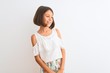 Young beautiful child girl wearing casual dress standing over isolated white background looking away to side with smile on face, natural expression. Laughing confident.
