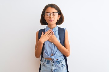 Sticker - Beautiful student child girl wearing backpack and glasses over isolated white background smiling with hands on chest with closed eyes and grateful gesture on face. Health concept.