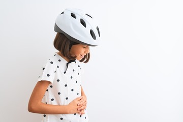 Sticker - Beautiful child girl wearing security bike helmet standing over isolated white background with hand on stomach because indigestion, painful illness feeling unwell. Ache concept.