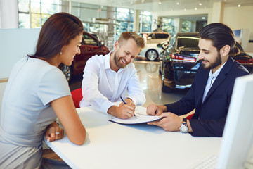 Wall Mural - Smiling man and woman buys a car in a car showroom.