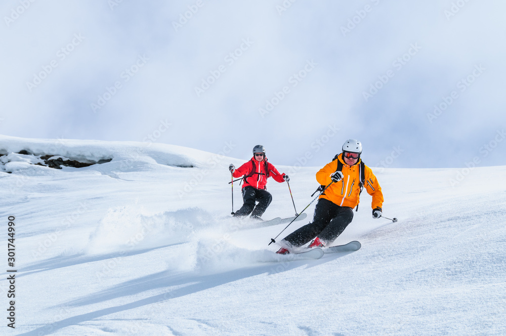 Zwei Skifahrer befahren gemeinsam einen steilen Hang - obrazy, fototapety, plakaty 