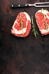 Wall Mural - Raw fresh meat Ribeye Steak, seasoning and meat fork on rustic background