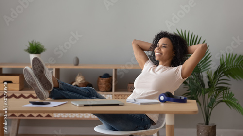 Fotografía Satisfied African American woman relaxing with legs on table