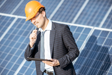 Wall Mural - businessman dressed in the suit with protective helmet working with digital tablet on a solar statio
