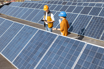 Wall Mural - two engineers or architects examining the construction of a solar power plant, standing with digital