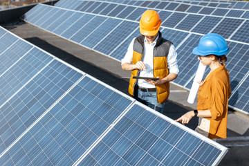 Wall Mural - two engineers or architects examining the construction of a solar power plant, standing with digital