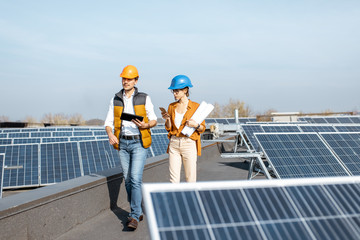 Wall Mural - two engineers or architects examining the construction of a solar power plant, walking with digital 