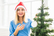 © satura_ - Happy young woman holding Christmas ball in front of Christmas tree.