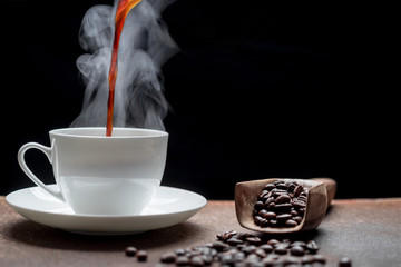 Wall Mural - Pouring coffee on a white cup with steam on dark background