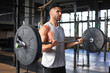 © ty - Muscular man working out in gym doing exercises with barbell at biceps.