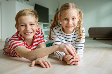 Wall Mural - Portrait of two cheerful children laying on the floor and playing with colorful dices