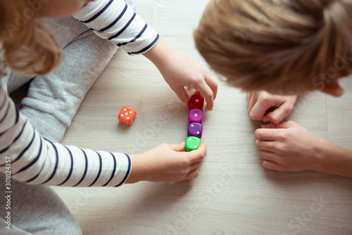 Cuadros en Lienzo Two clever children study mathematics playing with dices on the floor