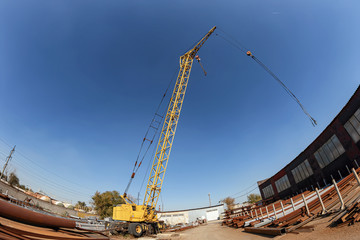 Wheeled yellow truck crane for loading heavy metal