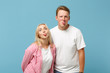 © ViDi Studio - Young cheerful couple two friends guy girl in white pink empty blank design t-shirts posing isolated on pastel blue background in studio. People lifestyle concept. Mock up copy space. Showing tongue.