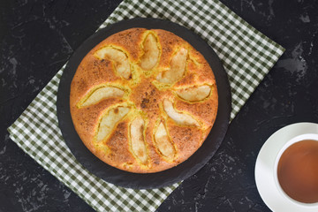 Homemade pear pie on a black table with pears in the background.