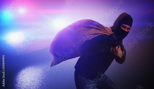 Cuadros en Lienzo Burglar or thief is running away. Police car is chasing him at n