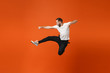 © ViDi Studio - Crazy young man in casual white t-shirt posing isolated on orange wall background studio portrait. People lifestyle concept. Mock up copy space. Having fun jumping, fooling around, clenching fists.