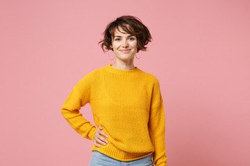 Wall Mural - Smiling young brunette woman girl in yellow sweater posing isolated on pastel pink wall background, studio portrait. People sincere emotions lifestyle concept. Mock up copy space. Looking camera.
