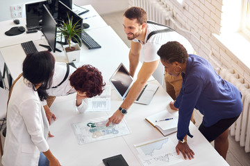 creative international team with computers, laptop stand and discuss financial issues of business project