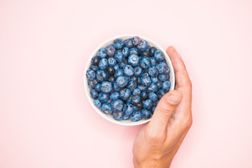 Wall Mural - The usefulness of blueberries. Closeup of blueberry berries with hands in a light dish background. Photo of blueberries for designers on the banner. Useful berries for vision. love for berries