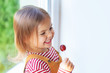 © mshynkarchuk - Portrait of cute toddler girl is sitting on windowstill with loly pop.