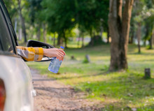 Woman Hand Hold A Blue Bottle From Car Window And Look Like She Will Throw The Bottle Out To Side Rode With Concept Of Safe Environment From Human Garbage.